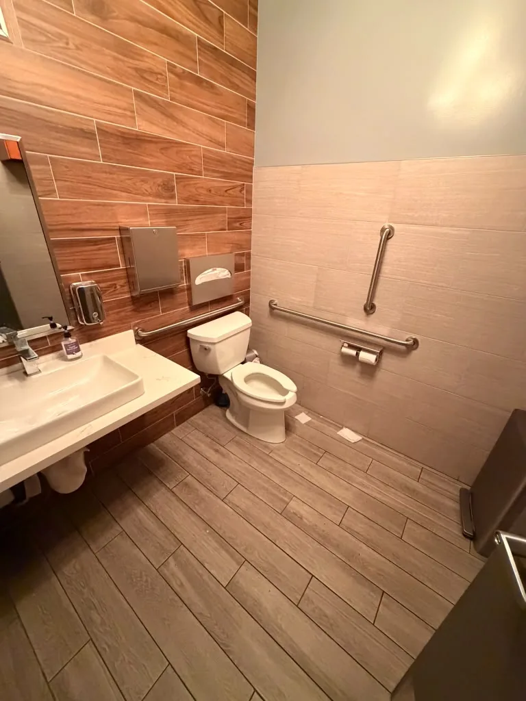 Accessible common-area restroom with wood-look tile at Avant Apartments