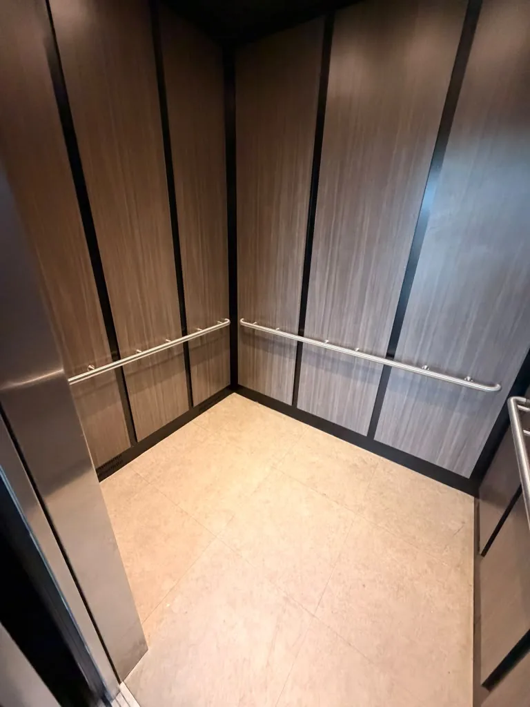 Elevator cab with wood-look panels and handrails at Avant Apartments
