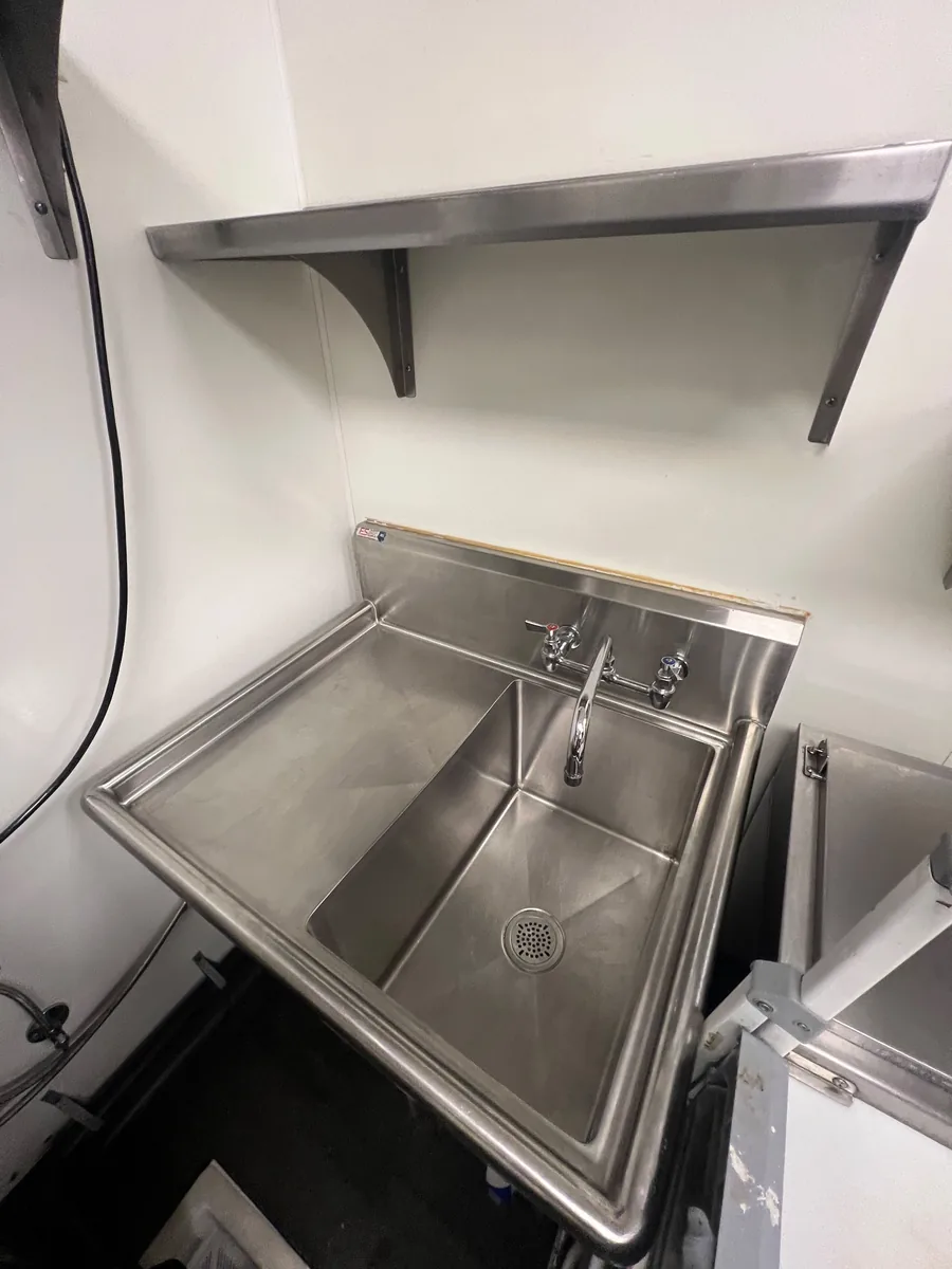 Stainless steel prep sink and wall shelf in a commercial kitchen