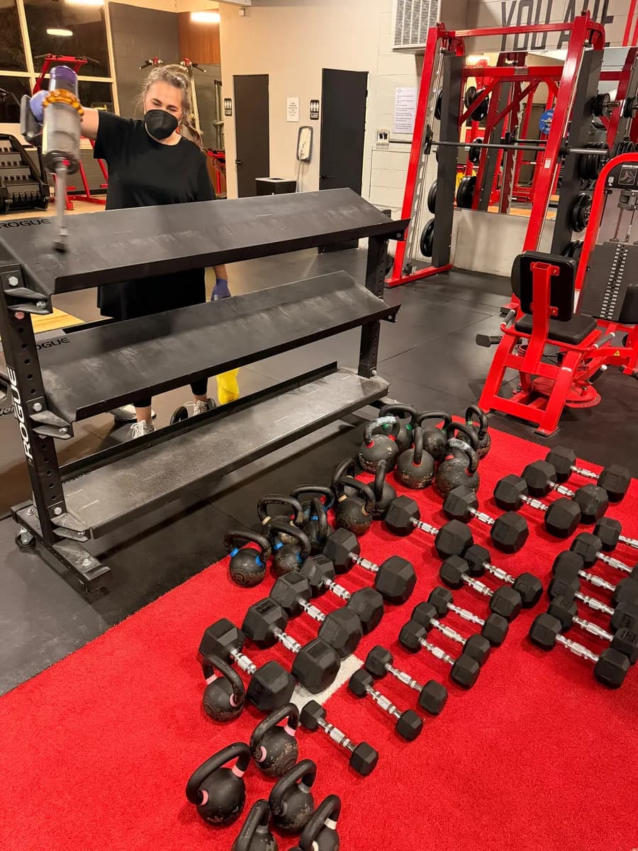 Cleaning kettlebell shelving on the turf area of a Seattle gym