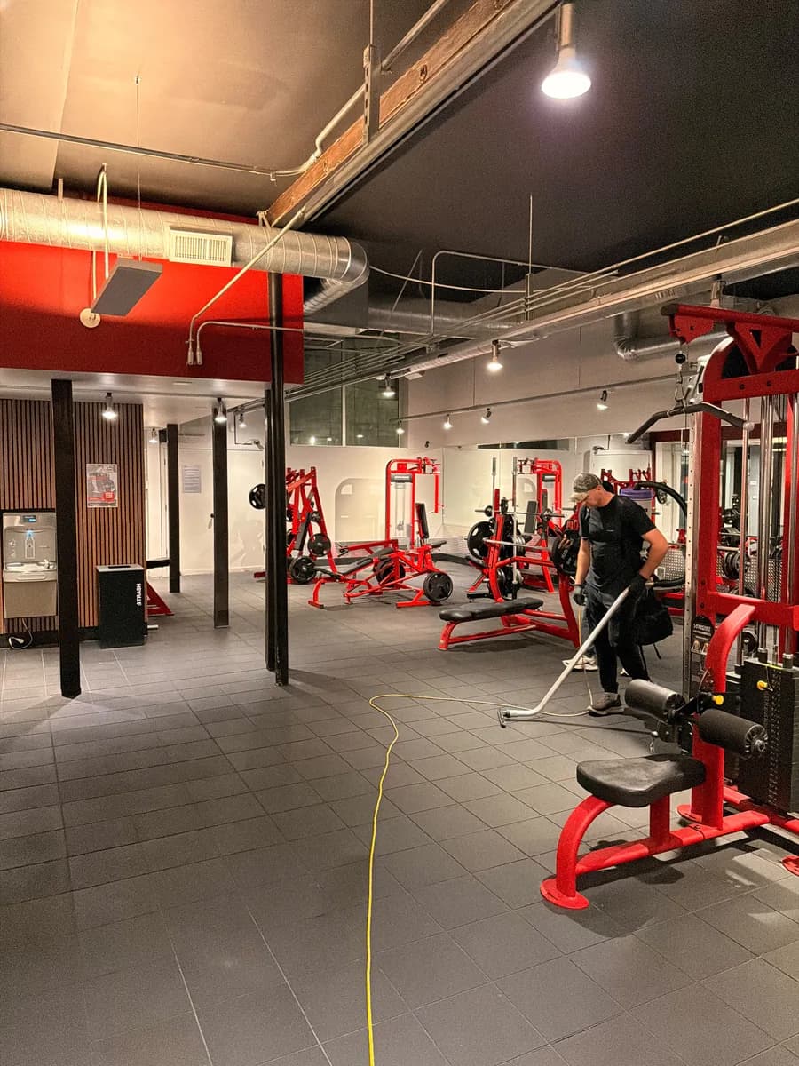 Crew member vacuuming the strength floor between machines at Transform 180