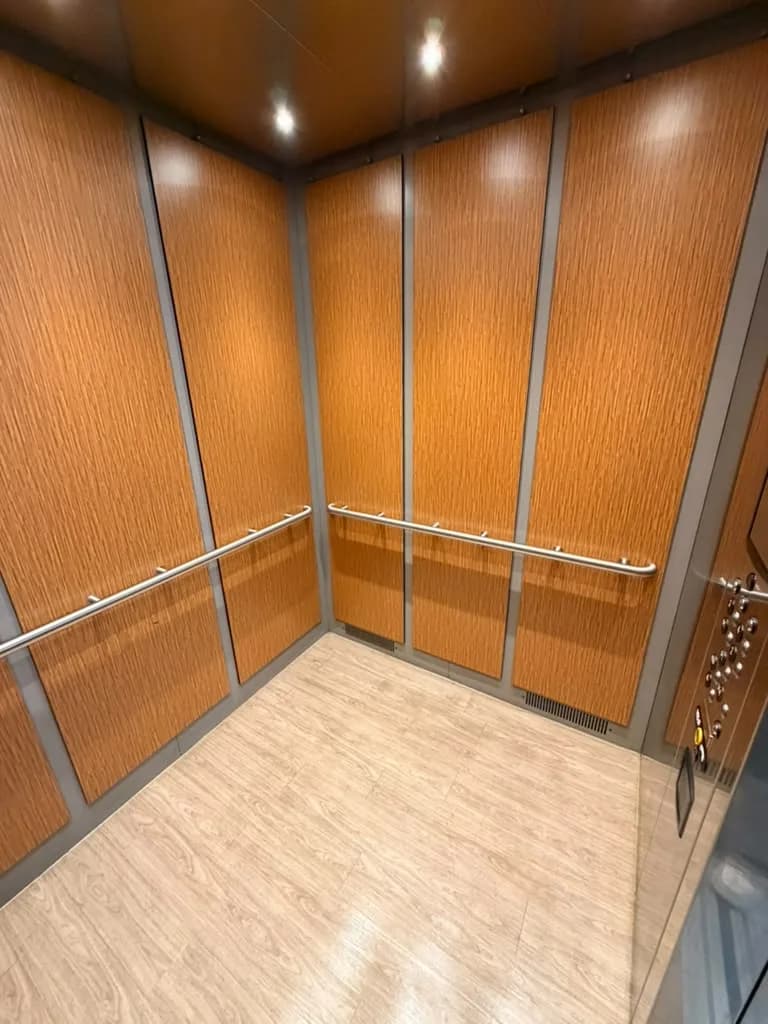 Elevator cab with wood panels and handrails at Verve Flats after cleaning